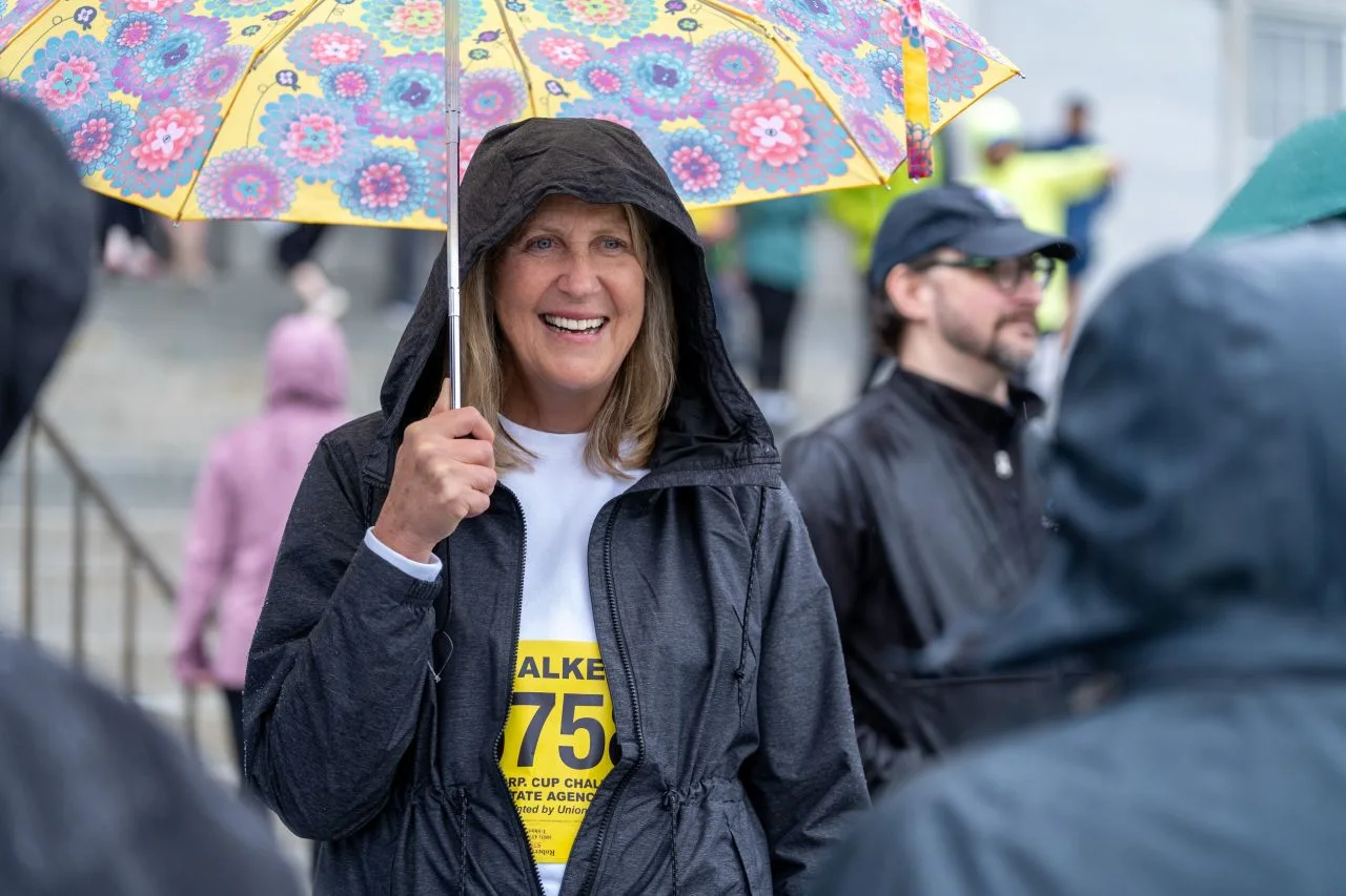 A participant walks beneath a colorful umbrella during the rainy Corporate Cup.