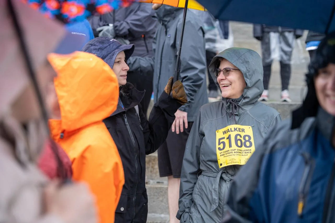 Two women talk beneath umbrellas during the Corporate Cup.