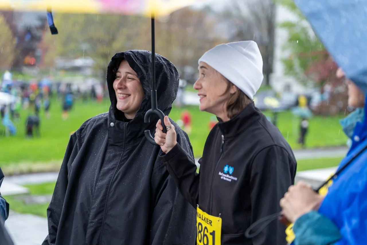 Two Corporate Cup participants talk beneath an umbrella.