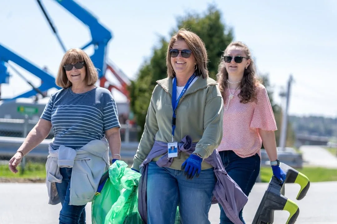 Three volunteers walk beside blue cleanup equipment.