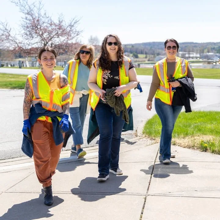 Four Green Up Day volunteers stand together in safety vests.