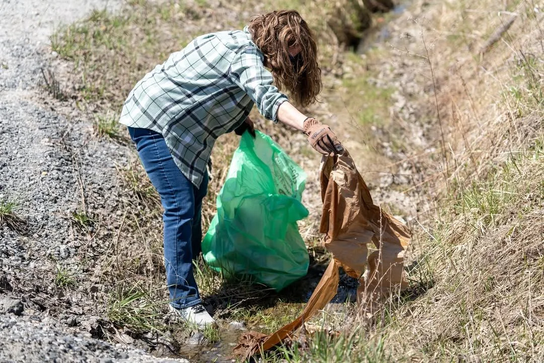 A volunteer collects roadside litter on Green Up Day.